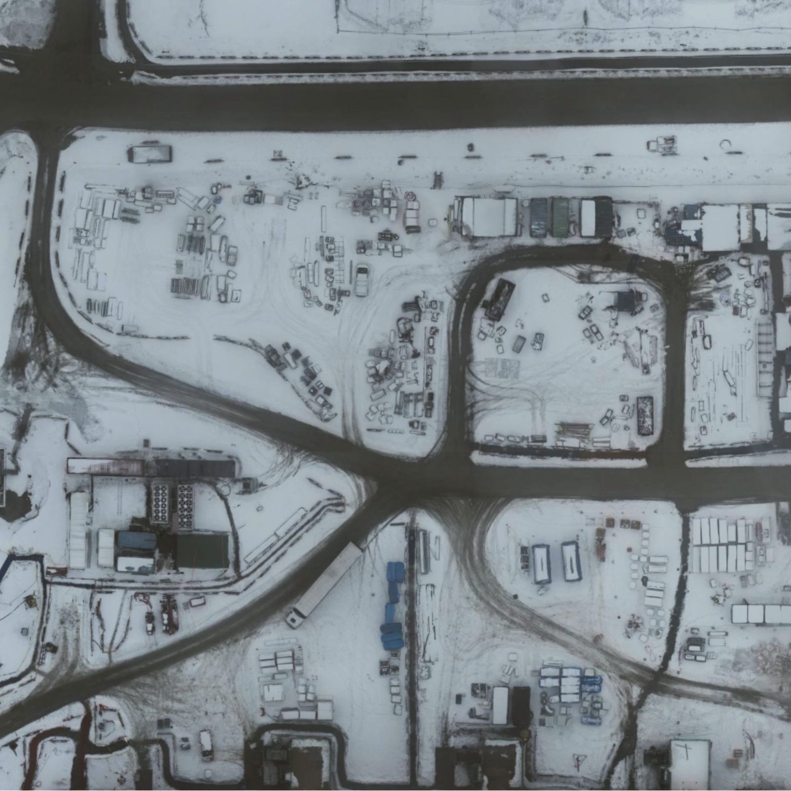 Byggeplads set lodret fra luften med snedækket terræn, skurby og oplagspladser