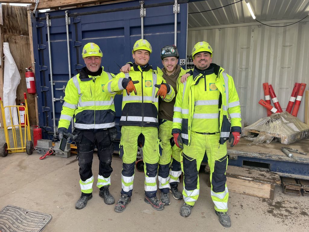 fire SiteHub-medarbejdere poserer for kameraet i fuld PPE på en byggeplads