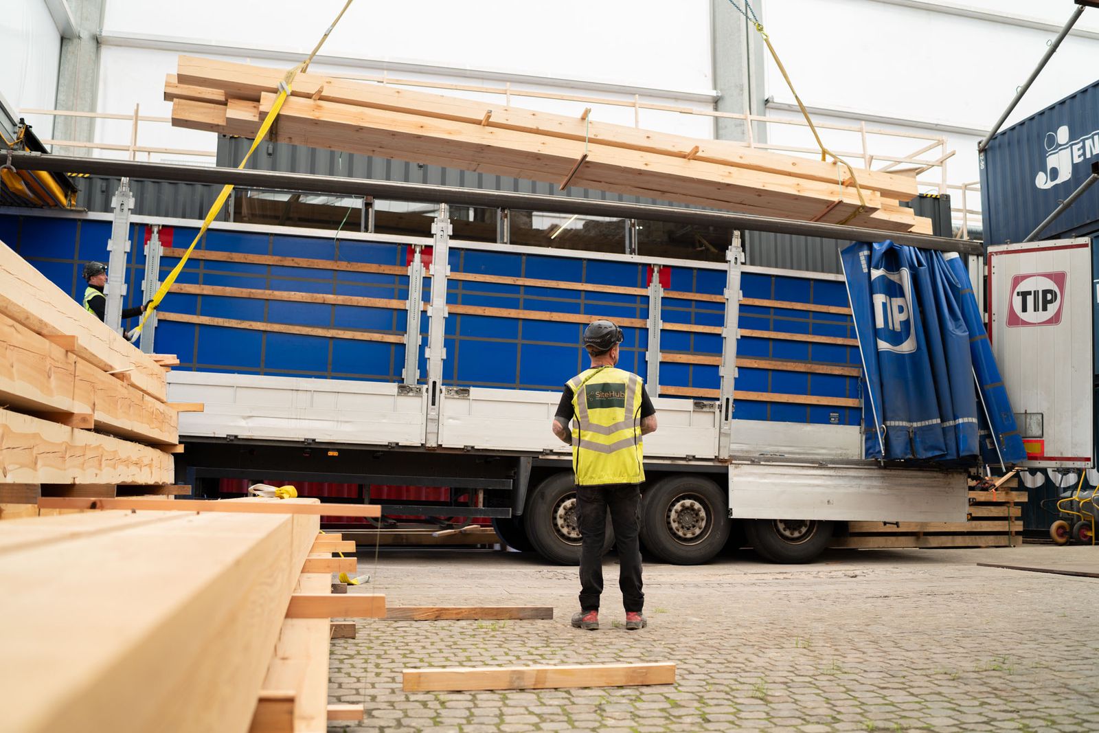 Pladsmedarbejder fra SiteHub tager imod en leverance af tømmer fra en lastbil
