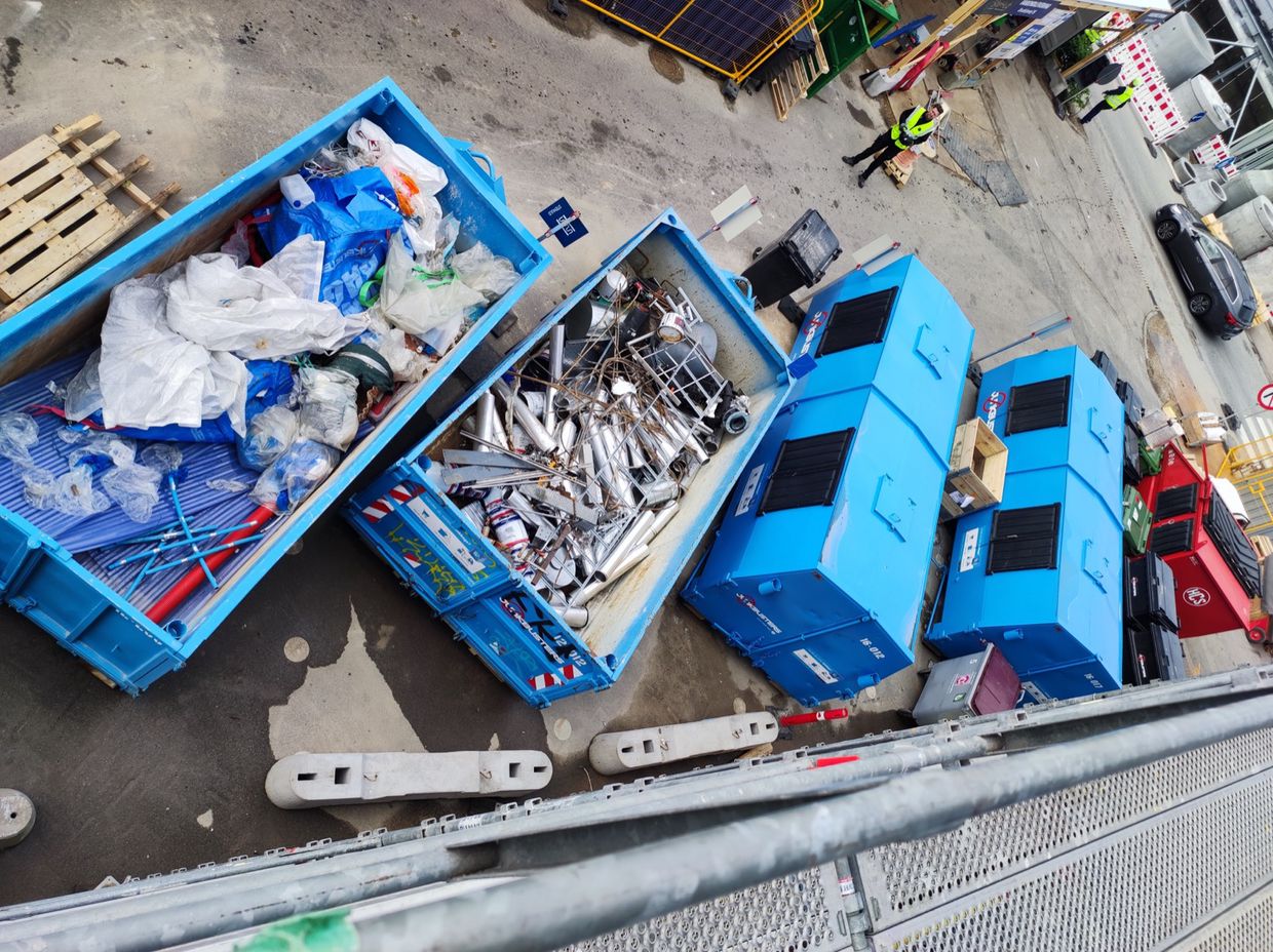 Åbne containere med sorteret plast og metal set fra oven på en pladsgård